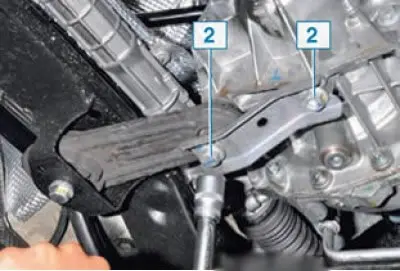 Otpustite vijke 2 koji pričvršćuju stražnji nosač motora na mjenjač (zamjenska glava 18,…