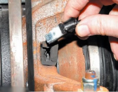 Извлечь датчик 2 скорости из отверстия крепления на поворотном кулаке, отжав отверткой язычок…