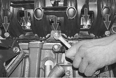 14. Using a 13 mm spanner, unscrew the three nuts and remove the two bolts securing the intake…