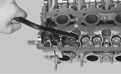 13. Install the valve spring compressor by screwing the camshaft bearing cap mounting bolt into one…