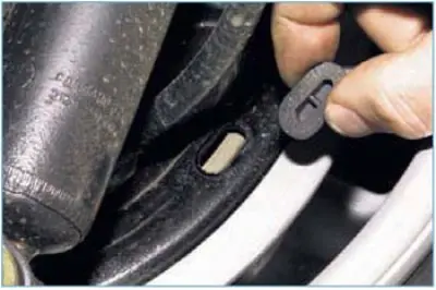 We use a screwdriver to pry off the plug on the brake shield...